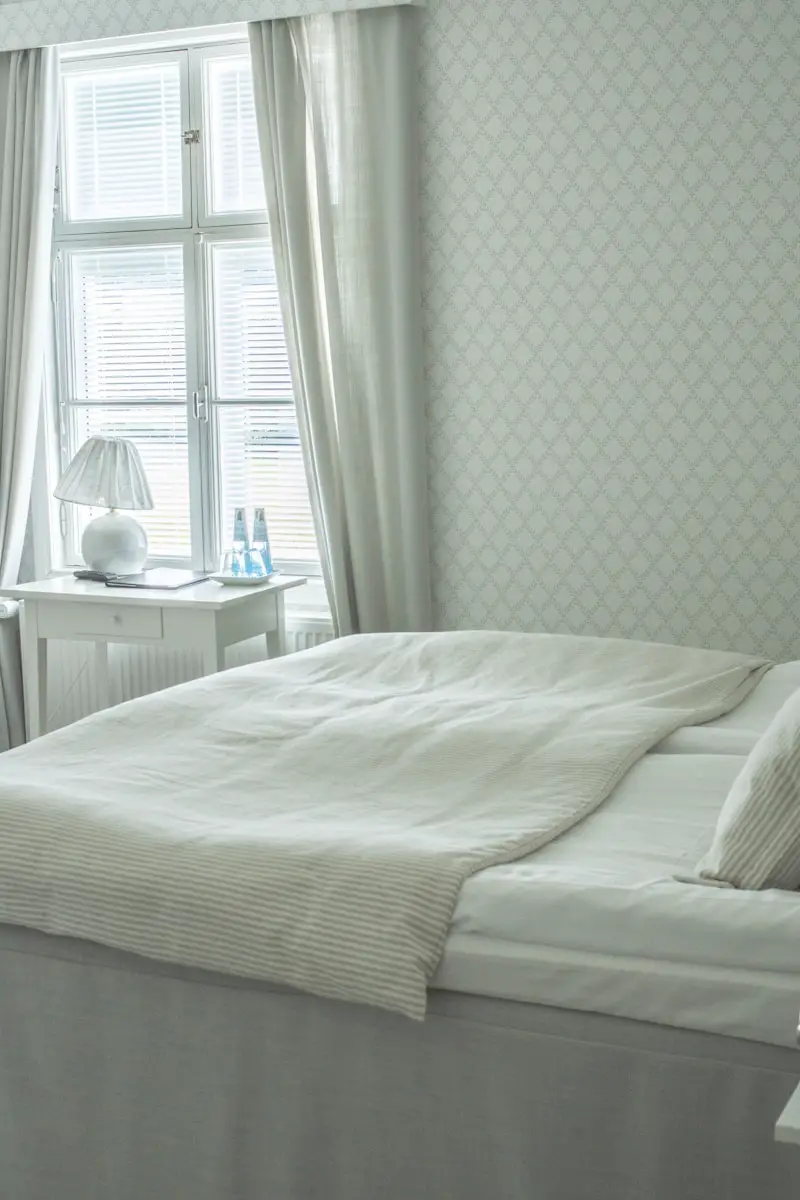white bed linen near white wooden nightstand